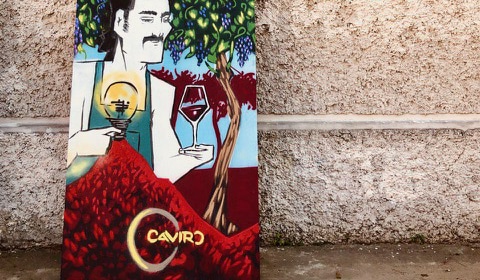 dipinto con uomo con calice e logo caviro